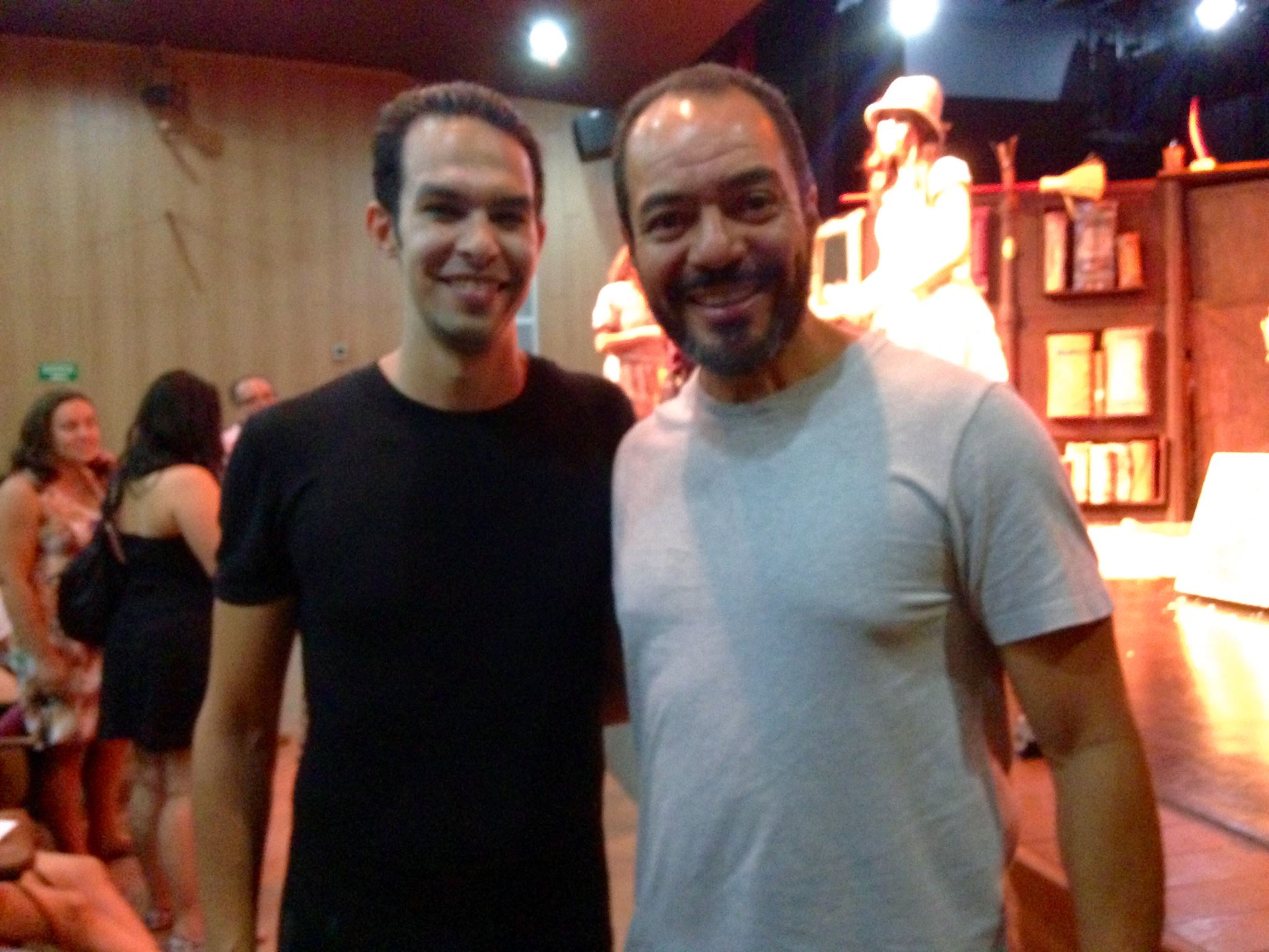 João Carlos Corrêa e Filipe Lima diante de um cenário teatral, em registro após atividade cênica