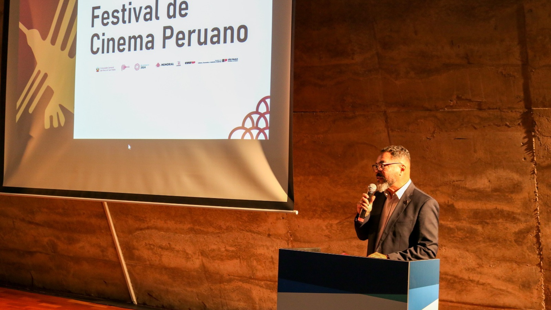 João Carlos Corrêa habla al micrófono ante una proyección del Festival de Cinema Peruano