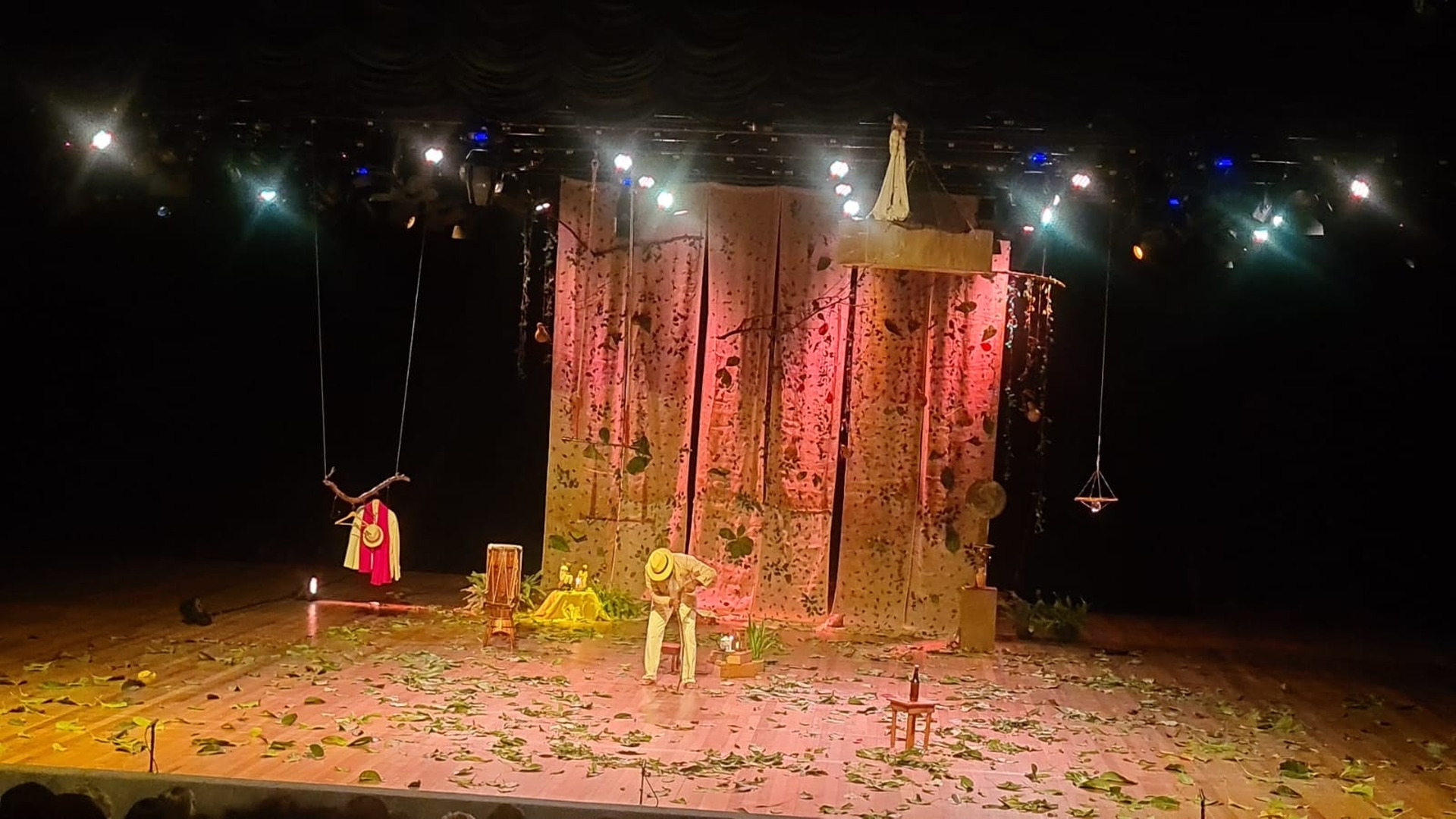 Escenario teatral con cortinas rojas, objetos escénicos e iluminación nocturna