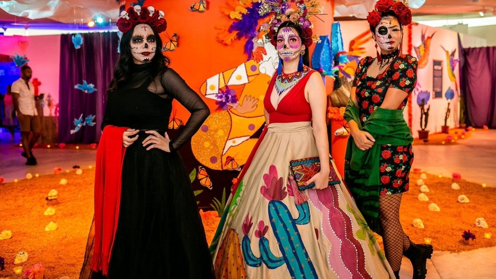 Grupo de participantes caracterizados como catrinas posa ante un decorado colorido de una celebración cultural mexicana