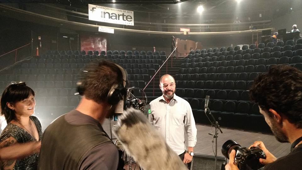 Entrevista e registro de atividade no teatro do Complexo Cultural Funarte de Brasília, com a sinalização da Funarte ao fundo
