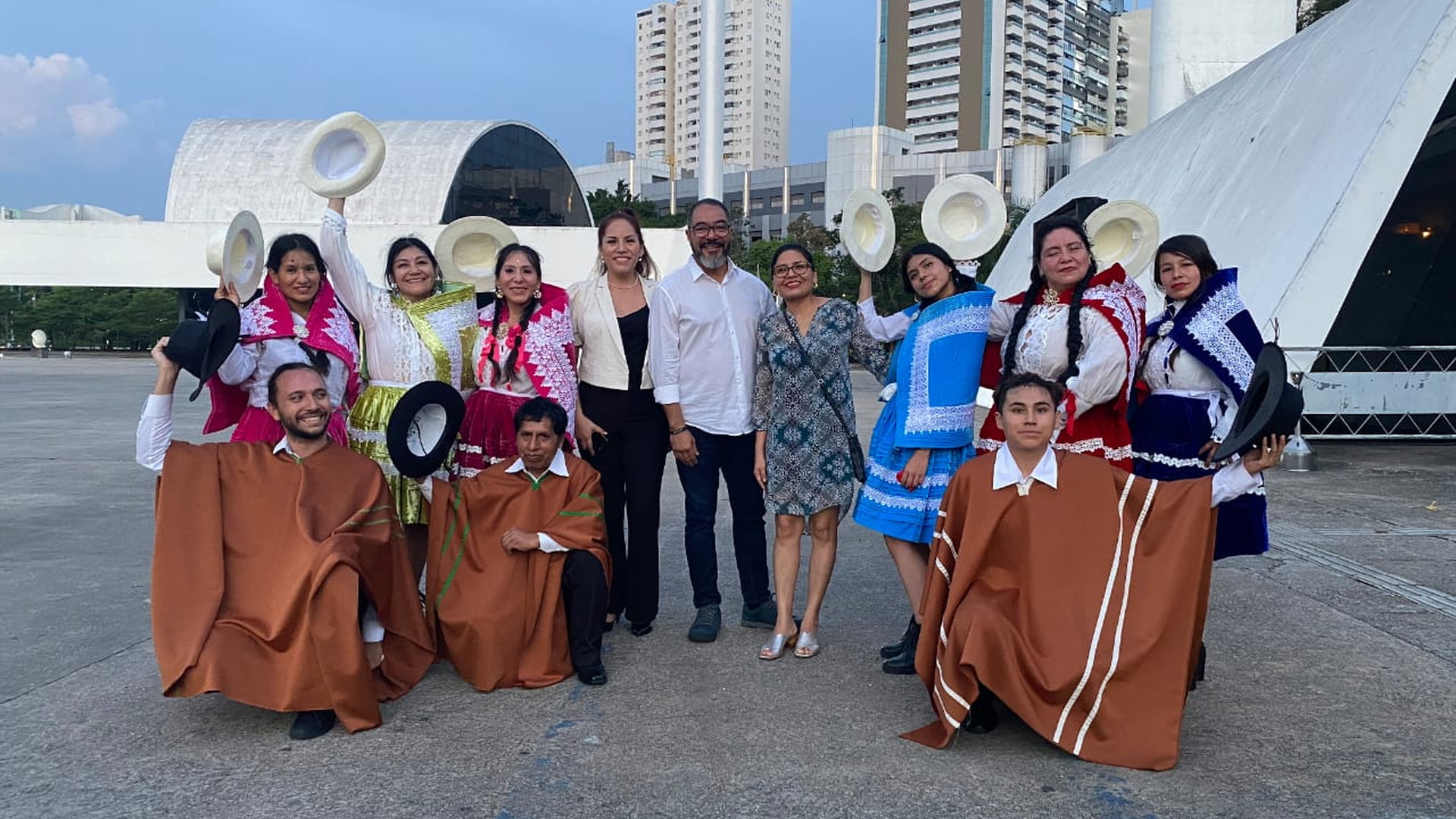Grupo de artistas con trajes tradicionales posa en el área exterior del Memorial junto a elementos arquitectónicos