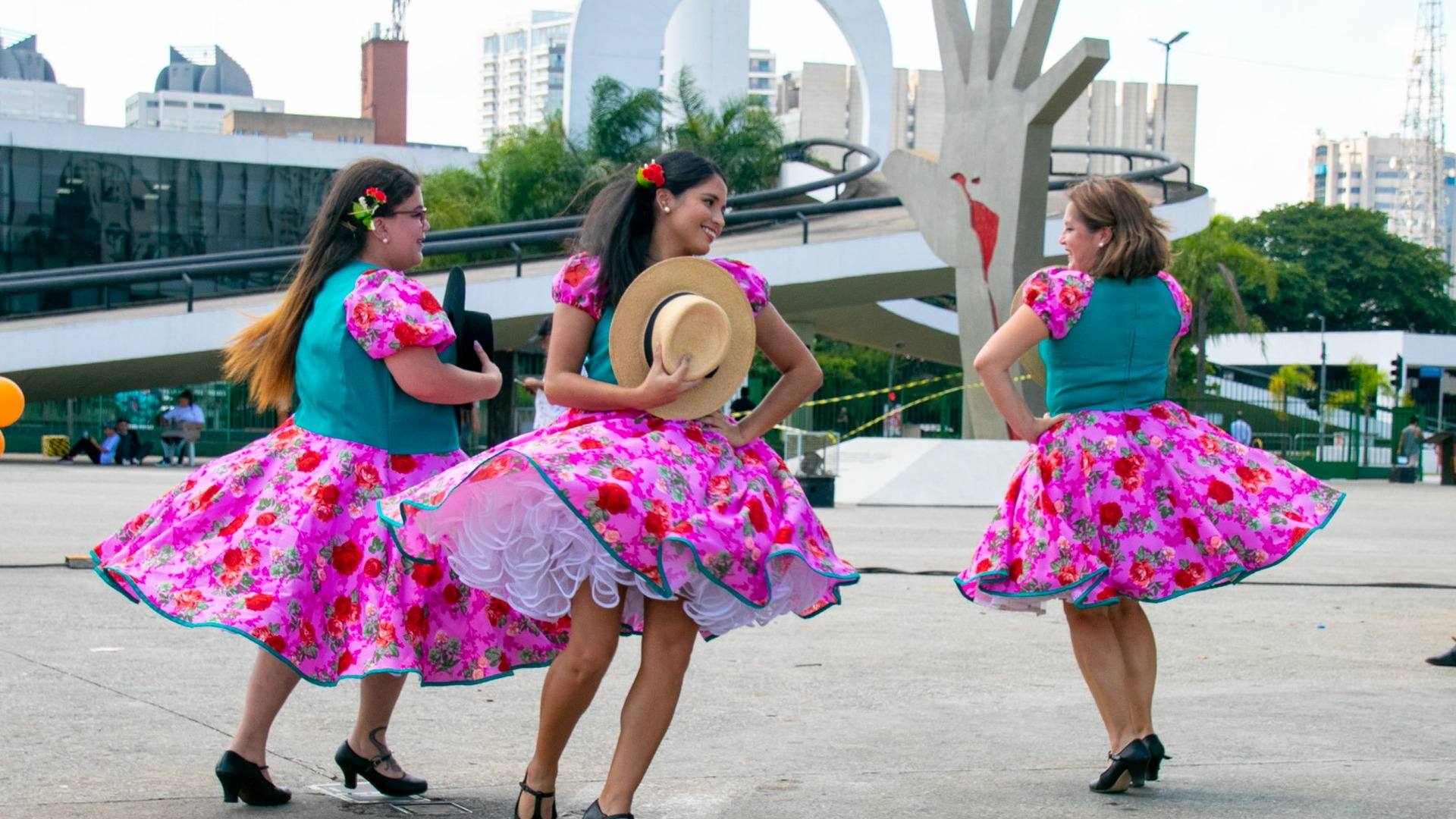 Tres bailarinas con faldas coloridas presentan una coreografía en la plaza del Memorial da América Latina
