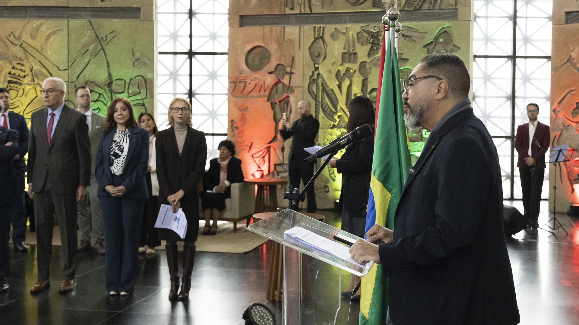 Autoridades e invitados acompañan un discurso en un ambiente interior decorado para una celebración cultural