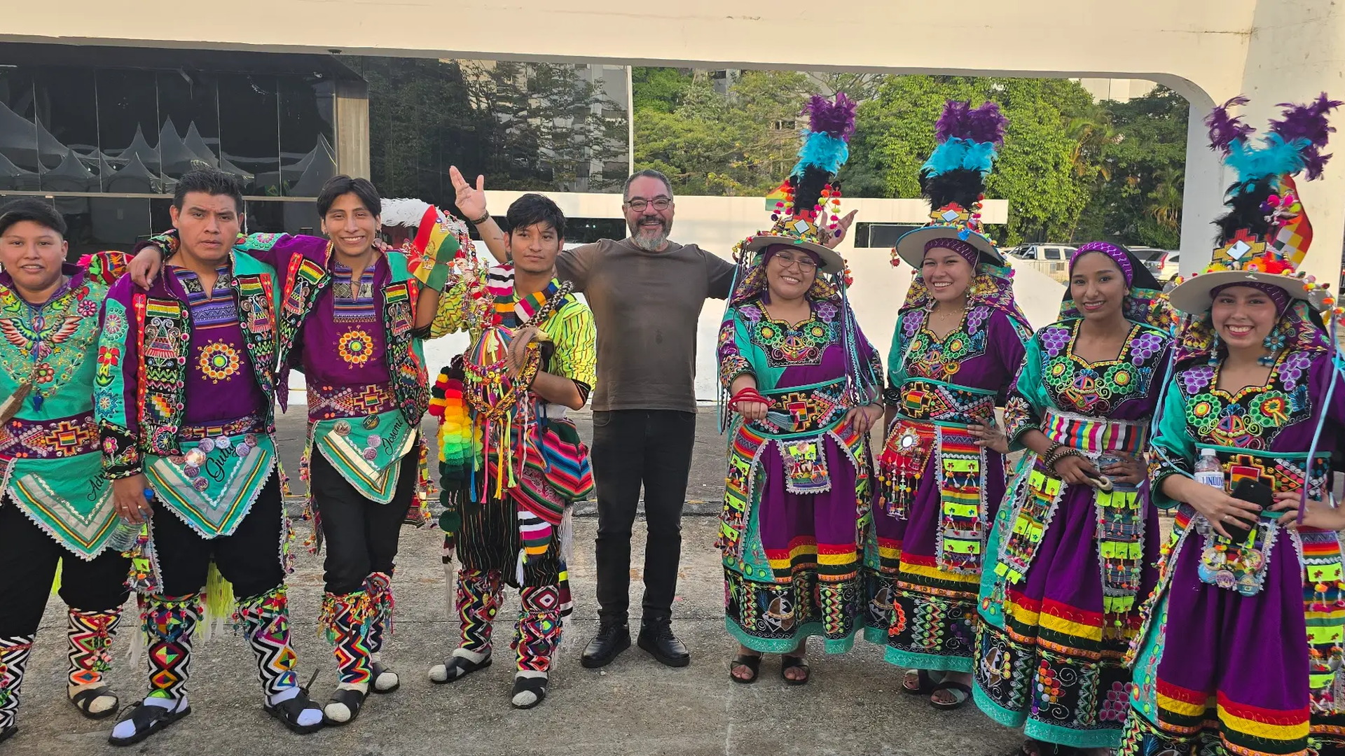 Grupo de artistas con trajes tradicionales coloridos posa en el área exterior del Memorial da América Latina