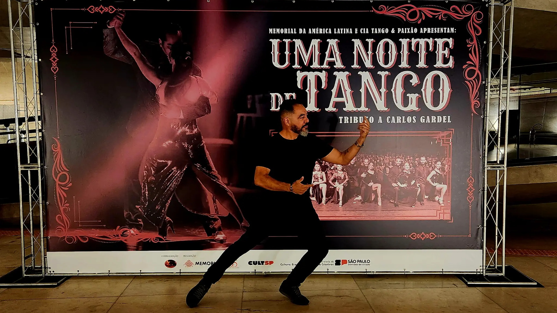 João Carlos Corrêa posa ante el panel del espectáculo Uma Noite de Tango, con la imagen de una pareja bailando