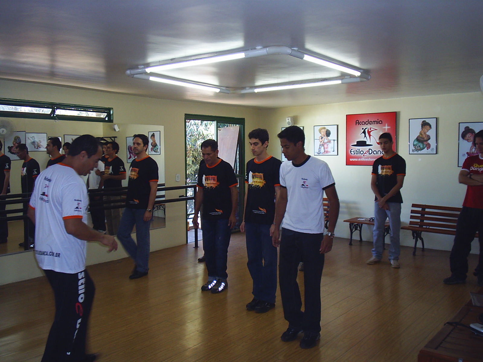 Turma pratica passos em formação diante dos espelhos do salão da Academia Estilo e Dança