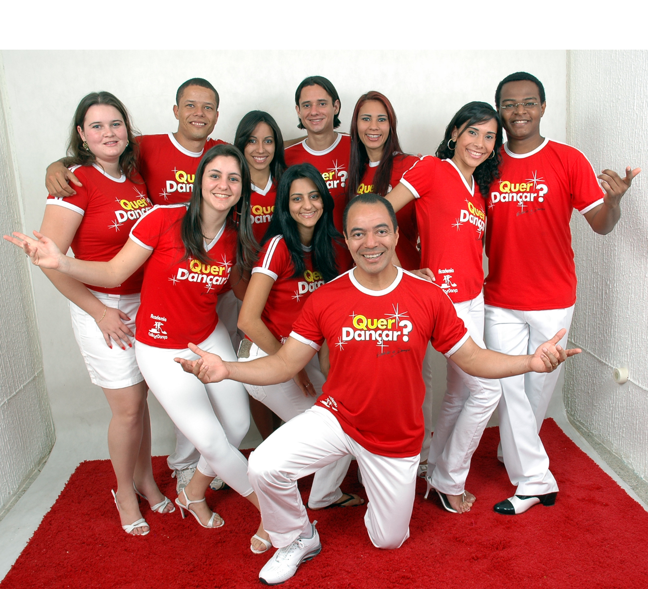 Grupo de integrantes com camisetas vermelhas da campanha Quer Dançar reunido em retrato coletivo