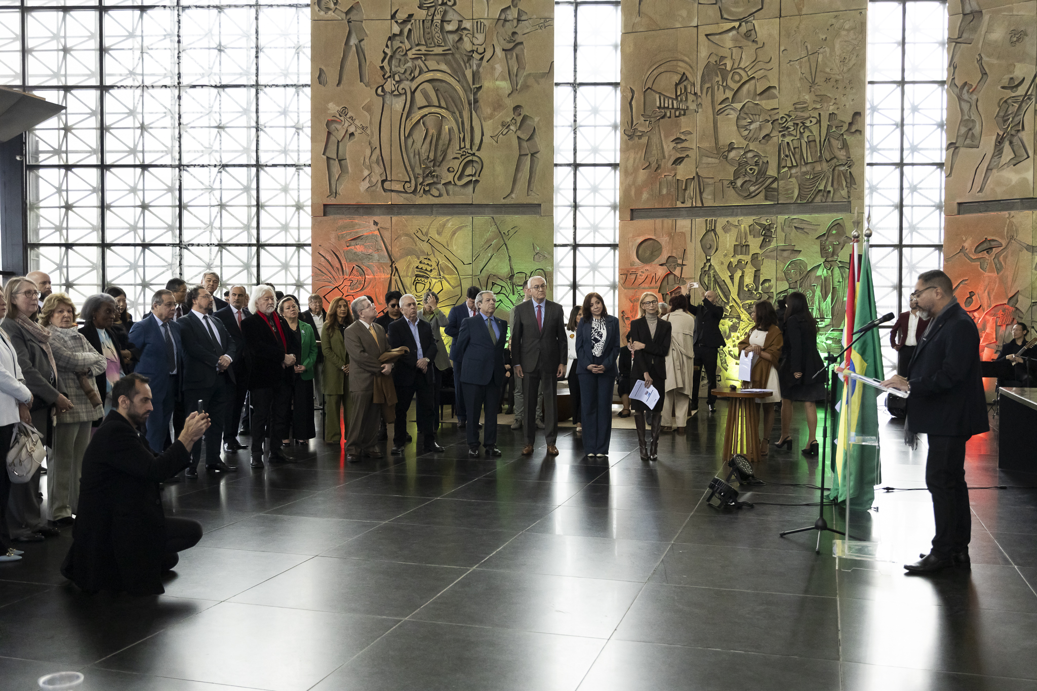 Participante habla desde un atril ante el público y las banderas de Bolivia y Brasil durante la ceremonia