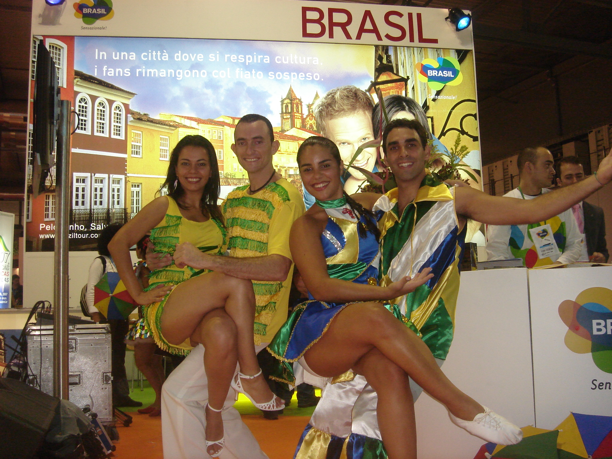 Dois casais de integrantes do Grupo Brasilidade posam com figurinos de apresentação diante do estande do Brasil em Milão, em 2007
