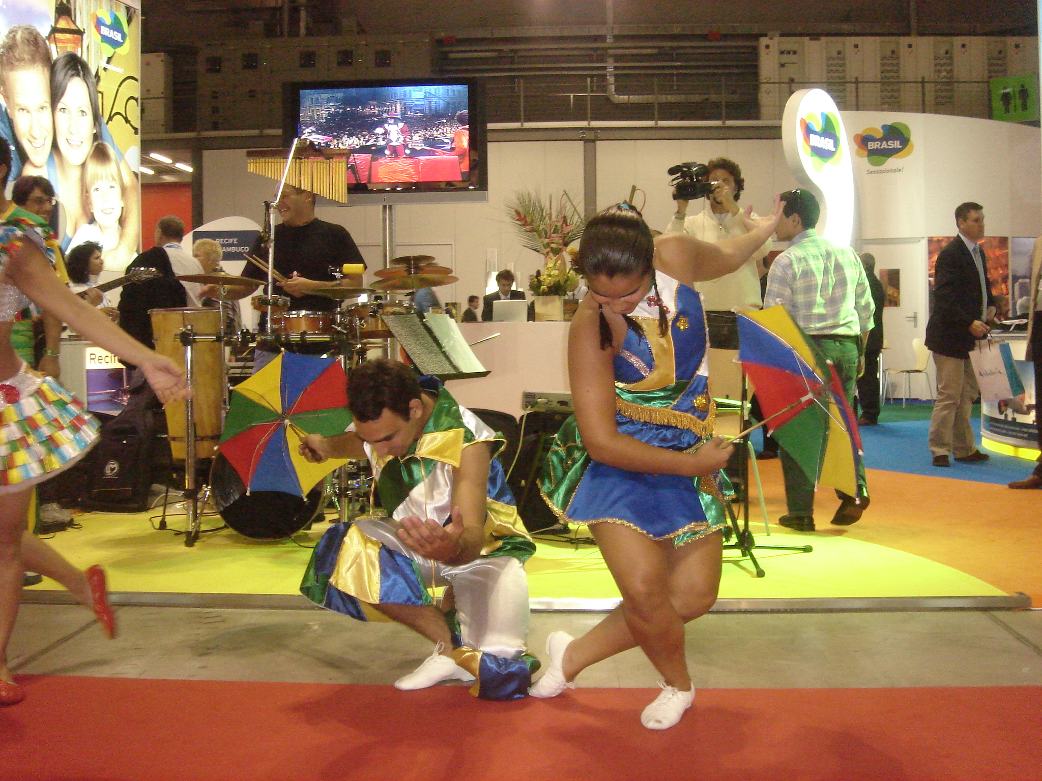 Dupla do Grupo Brasilidade realiza cena coreográfica com sombrinhas coloridas no estande do Brasil em Milão, em 2007
