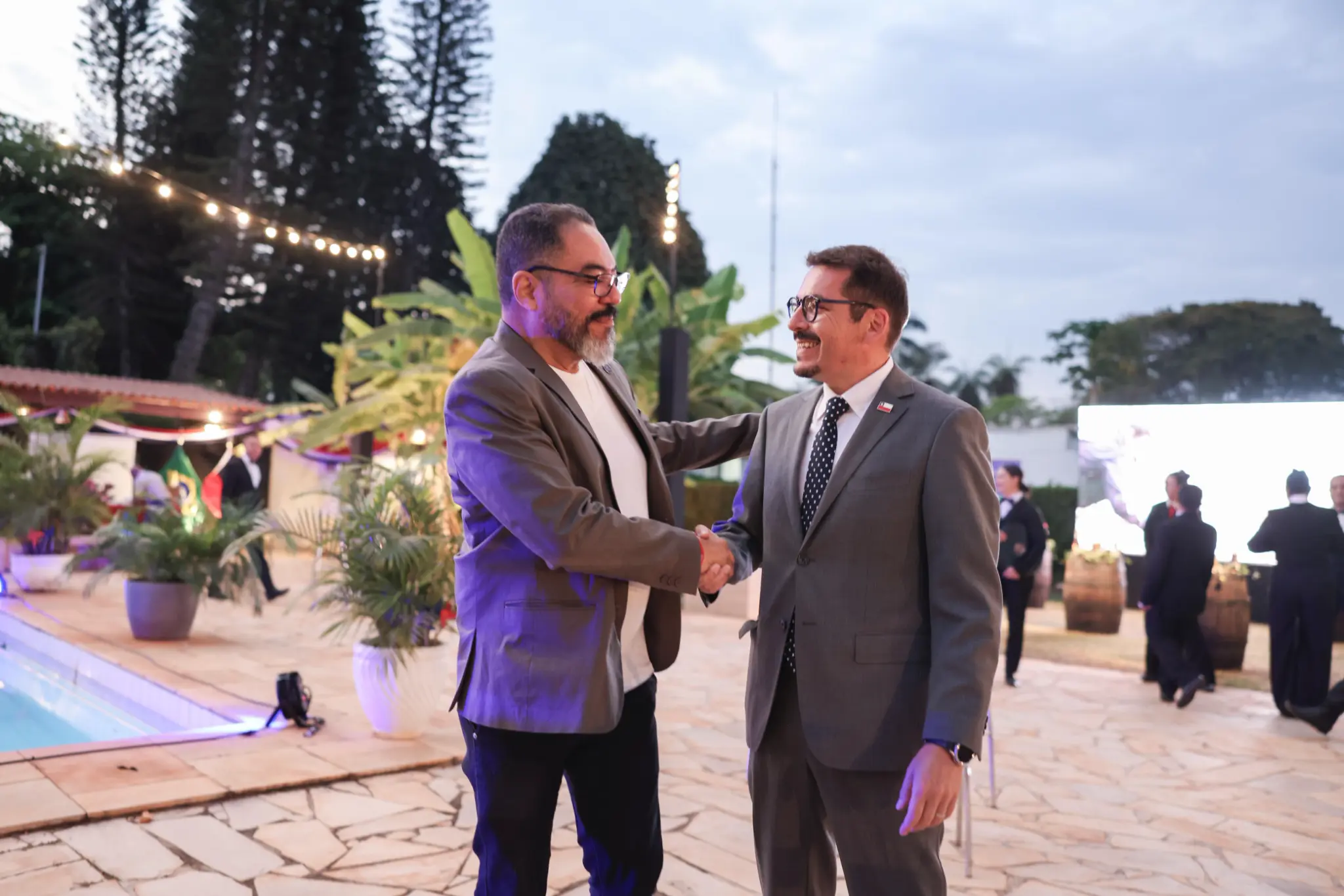 João Carlos Corrêa y Sebastián Depolo sonríen y se estrechan las manos durante un evento al aire libre en Brasilia