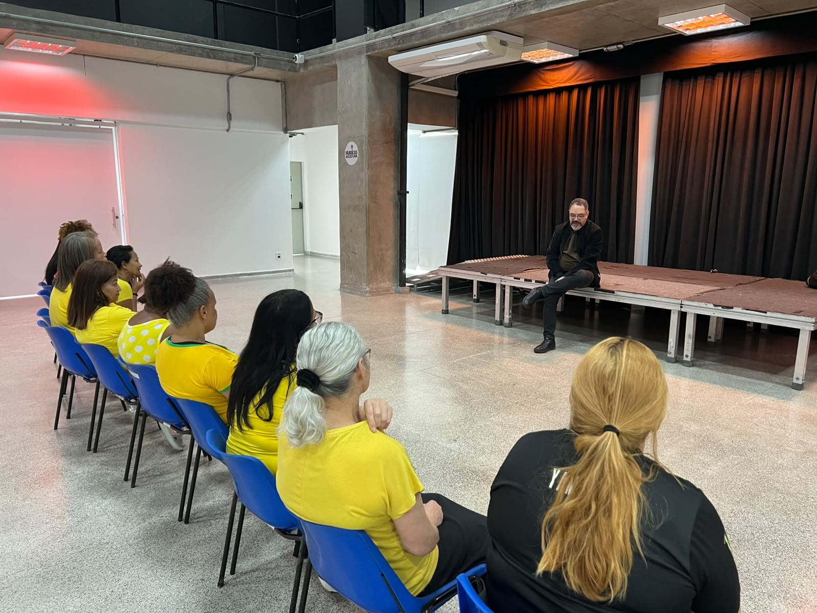 João Carlos Corrêa conversa com participantes reunidos diante do palco na Fábrica de Cultura Itaim Paulista