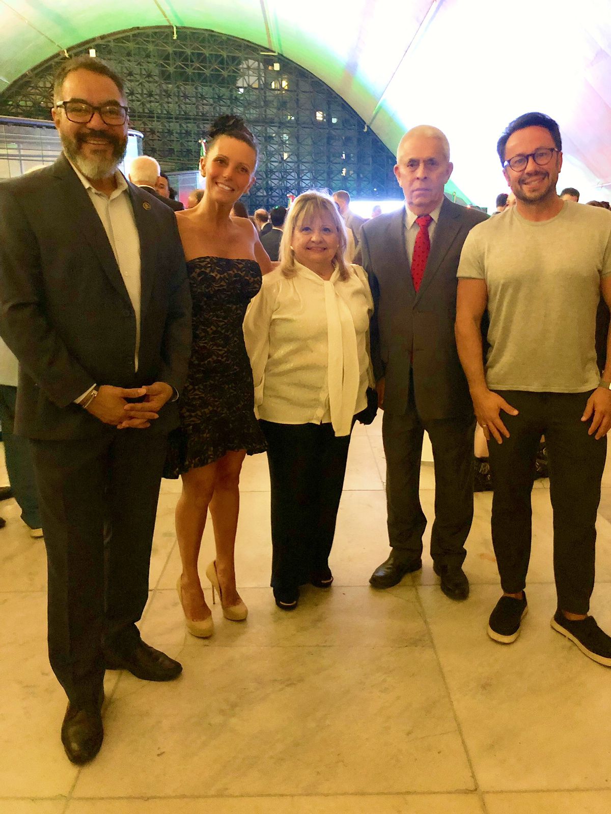 João Carlos Corrêa y cuatro participantes posan juntos durante una recepción institucional en un salón de techo curvo