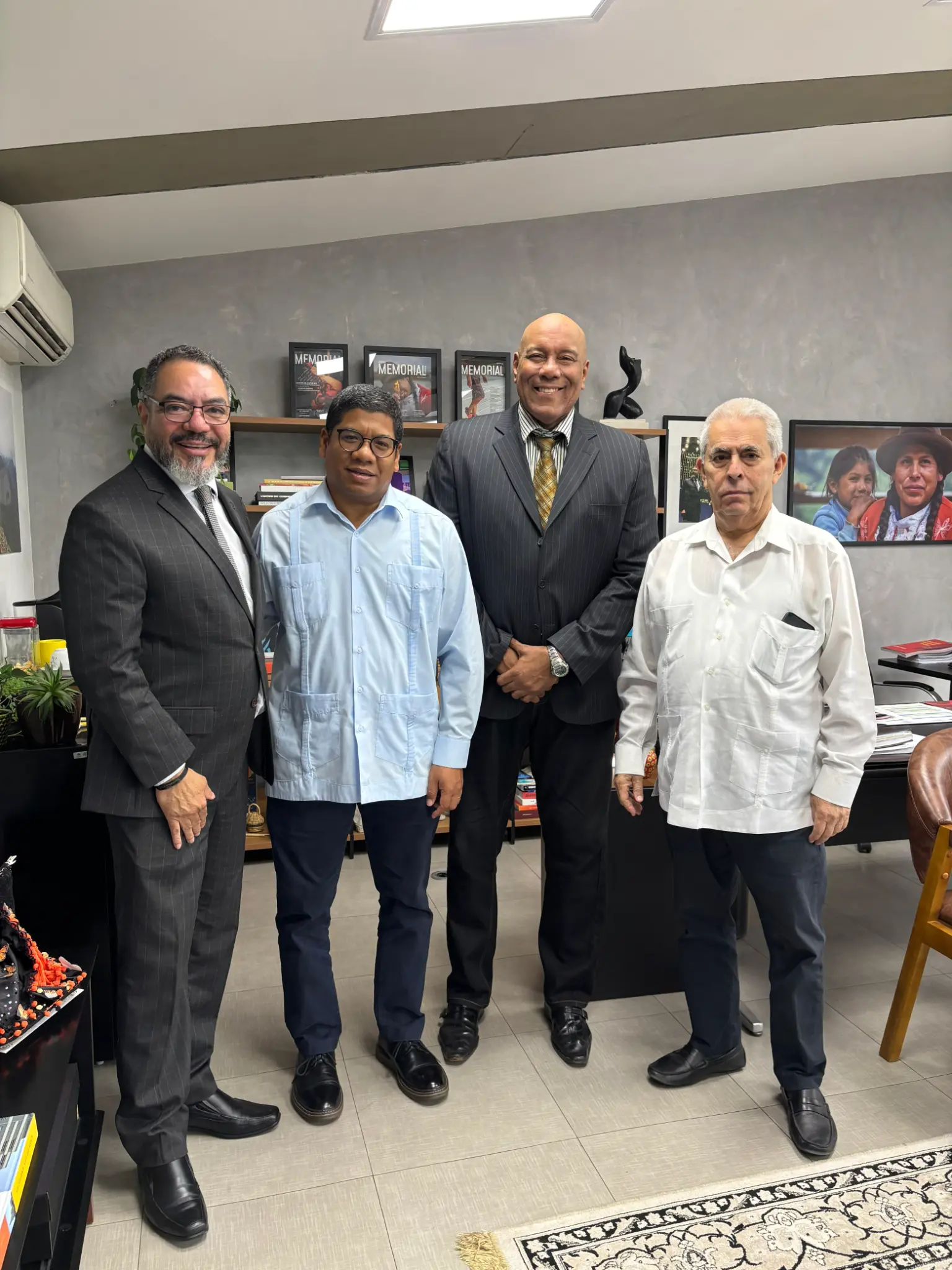 João Carlos Corrêa y tres participantes posan en una oficina del Memorial, frente a una estantería con publicaciones y fotografías