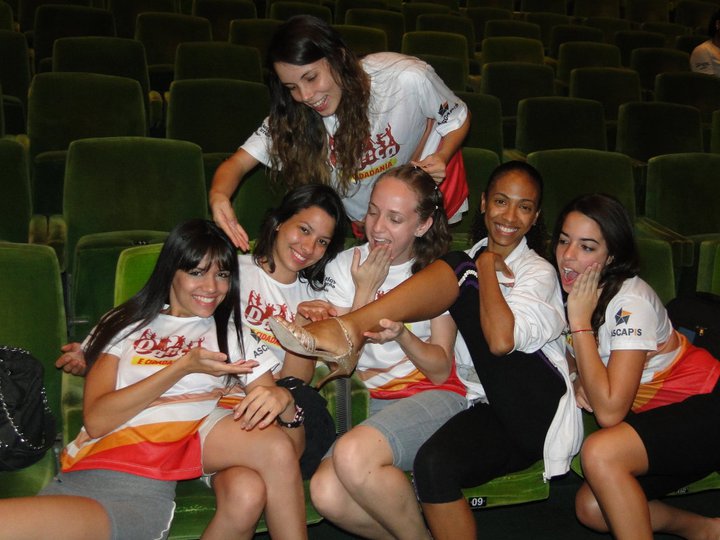 Seis participantes com camisetas do Projeto Dança e Cidadania em assentos de auditório