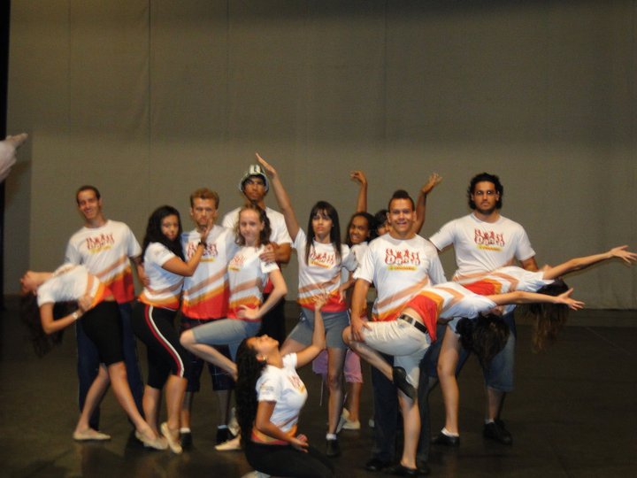 Dois jovens em figurinos coordenados executam movimento de dança durante apresentação