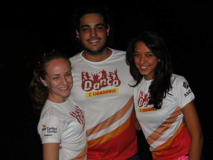 Dupla de jovens apresenta coreografia em palco com a identidade de Dança e Cidadania ao fundo
