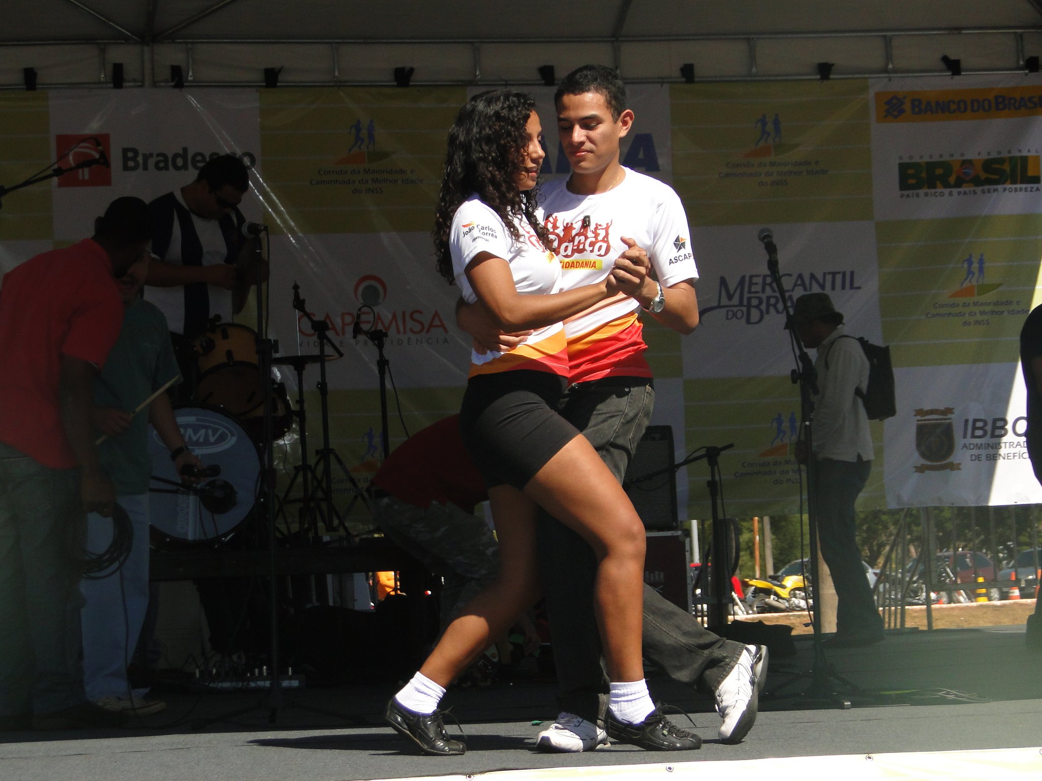 Dupla dança com figurinos branco e vermelho em apresentação de Dança e Cidadania