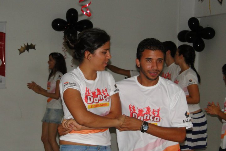 Dupla de participantes pratica dança com outros integrantes do Projeto Dança e Cidadania ao fundo