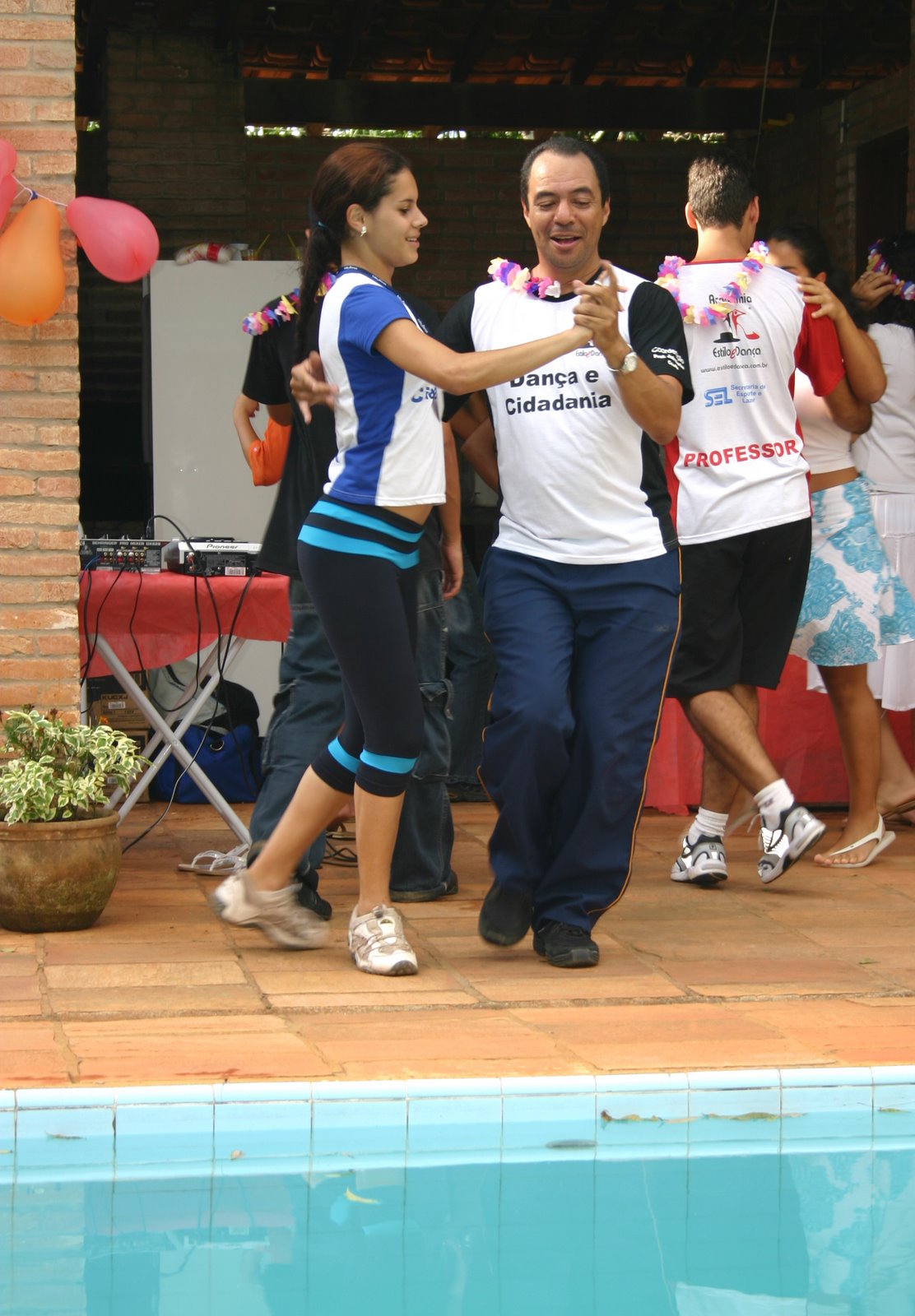 João Carlos Corrêa dança com uma jovem participante, ambos com camisetas do Projeto Dança e Cidadania