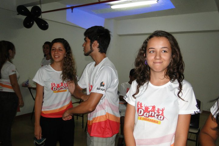 Participantes com camisetas do Projeto Dança e Cidadania reunidos em ambiente interno