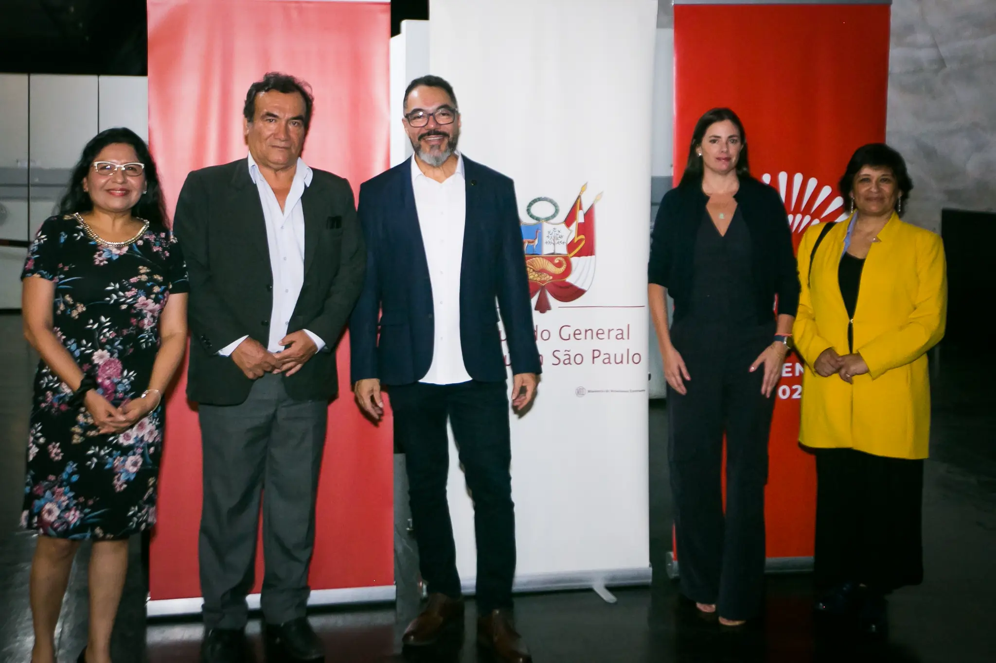 João Carlos Corrêa, Luis Armando Monteagudo Pacheco y tres invitadas posan frente a paneles institucionales con los colores del Perú