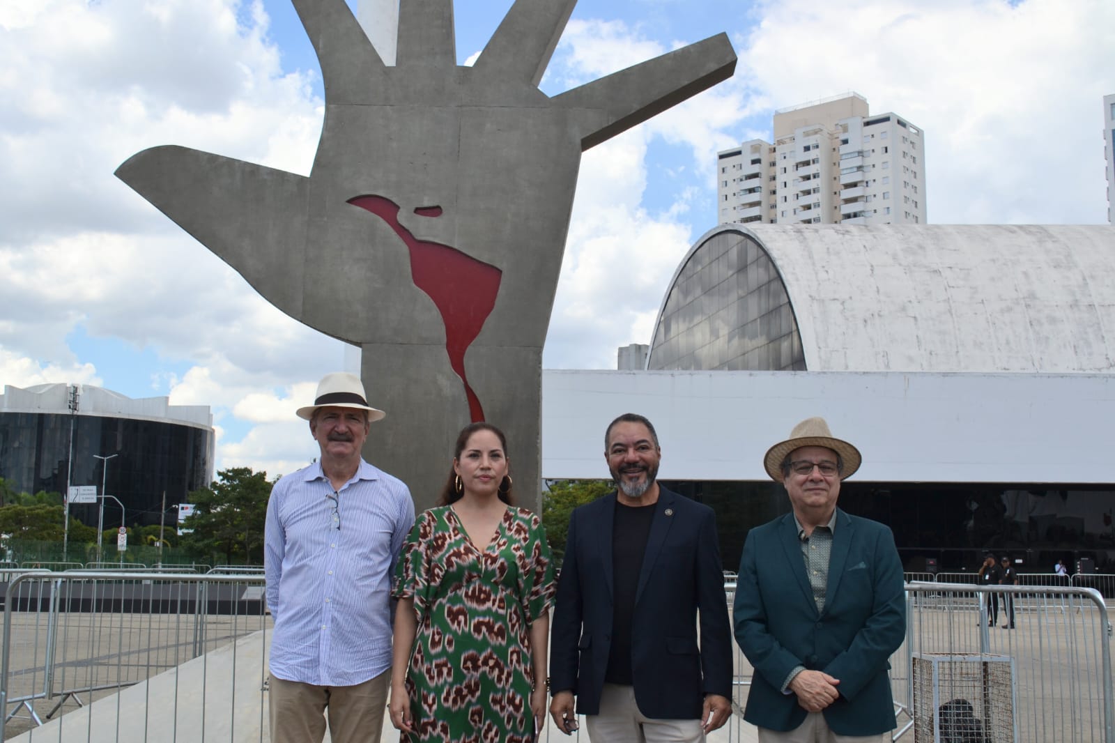 João Carlos Corrêa y tres visitantes posan frente al monumento A Mão y a la arquitectura del Memorial da América Latina