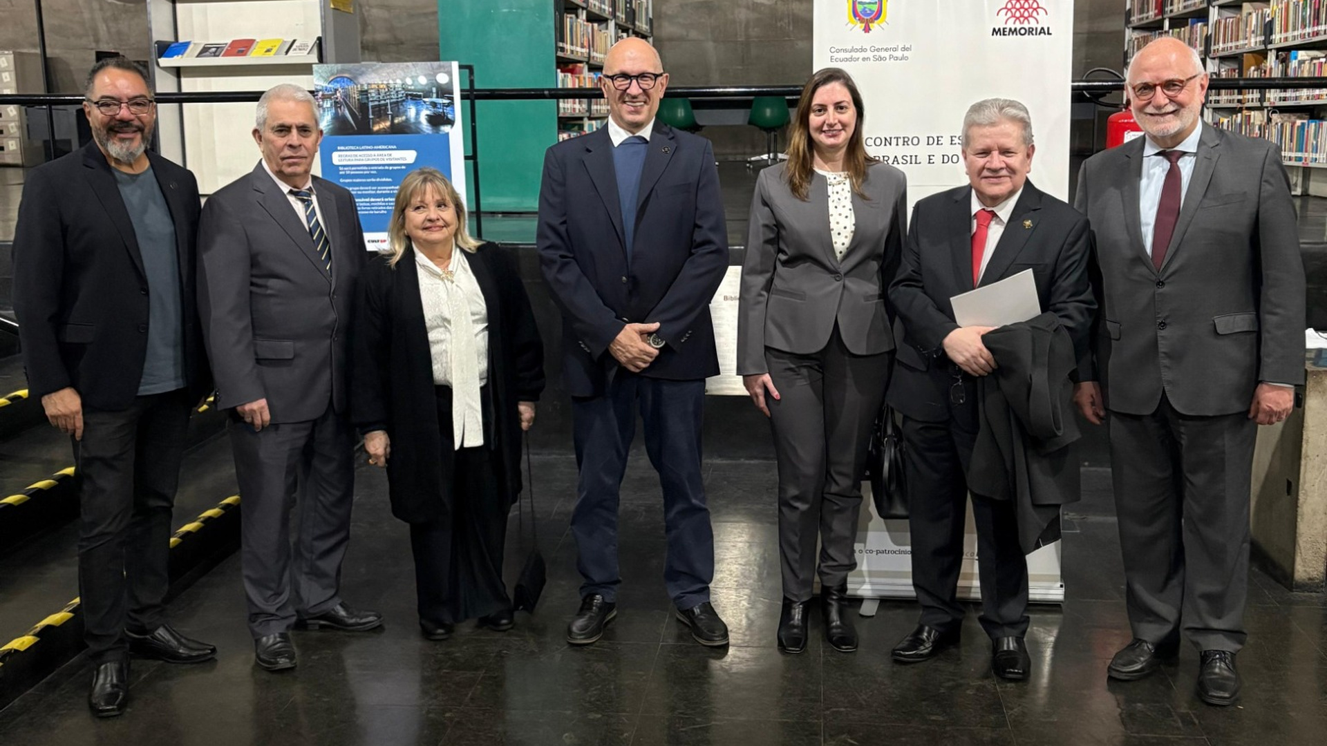 João Carlos Corrêa, representantes consulares e institucionales posan en la Biblioteca Latino-Americana ante los banners de Ecuador y del Memorial
