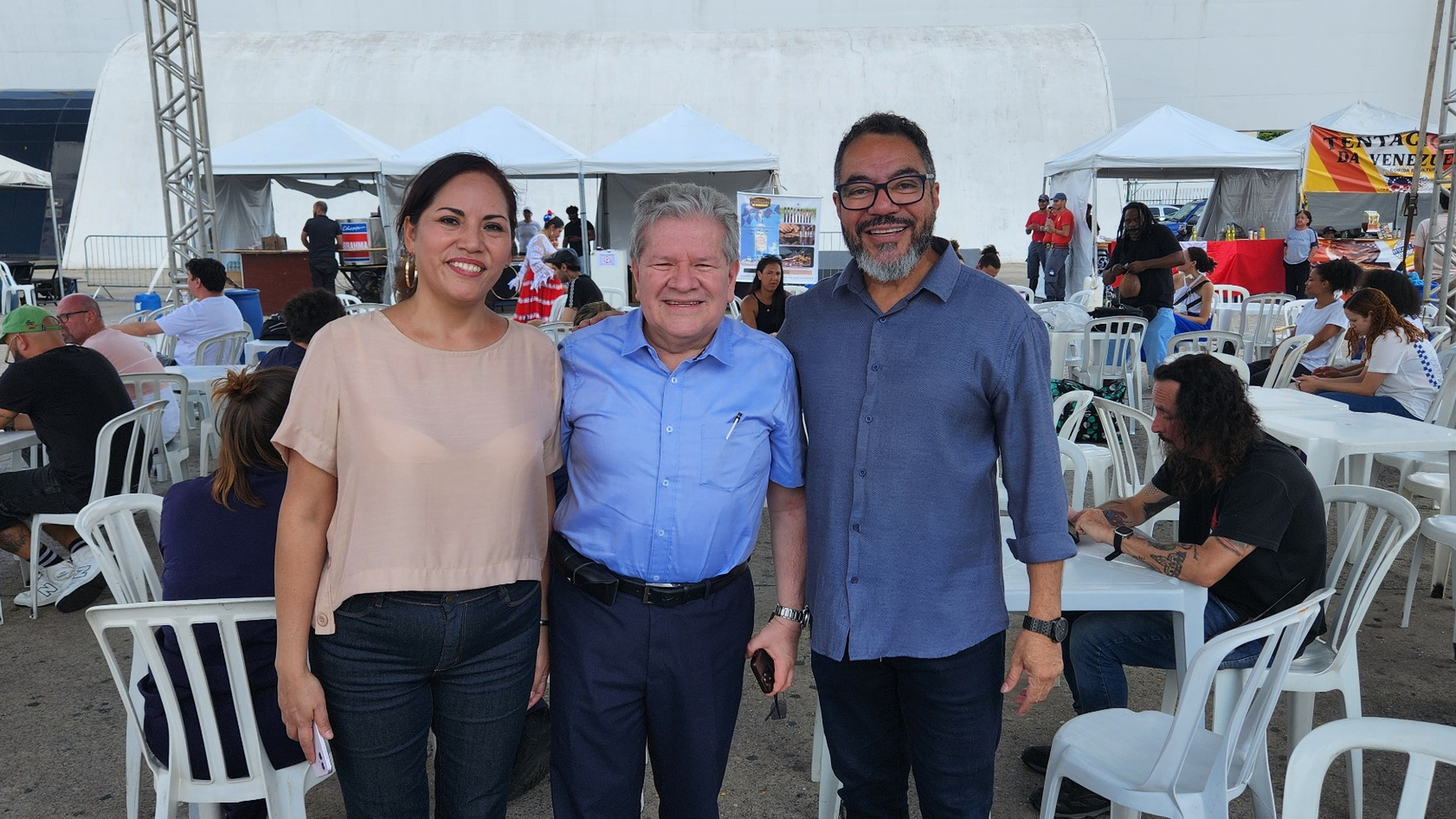 Eduardo Durán Cousin posa entre una participante y João Carlos Corrêa durante una programación cultural al aire libre