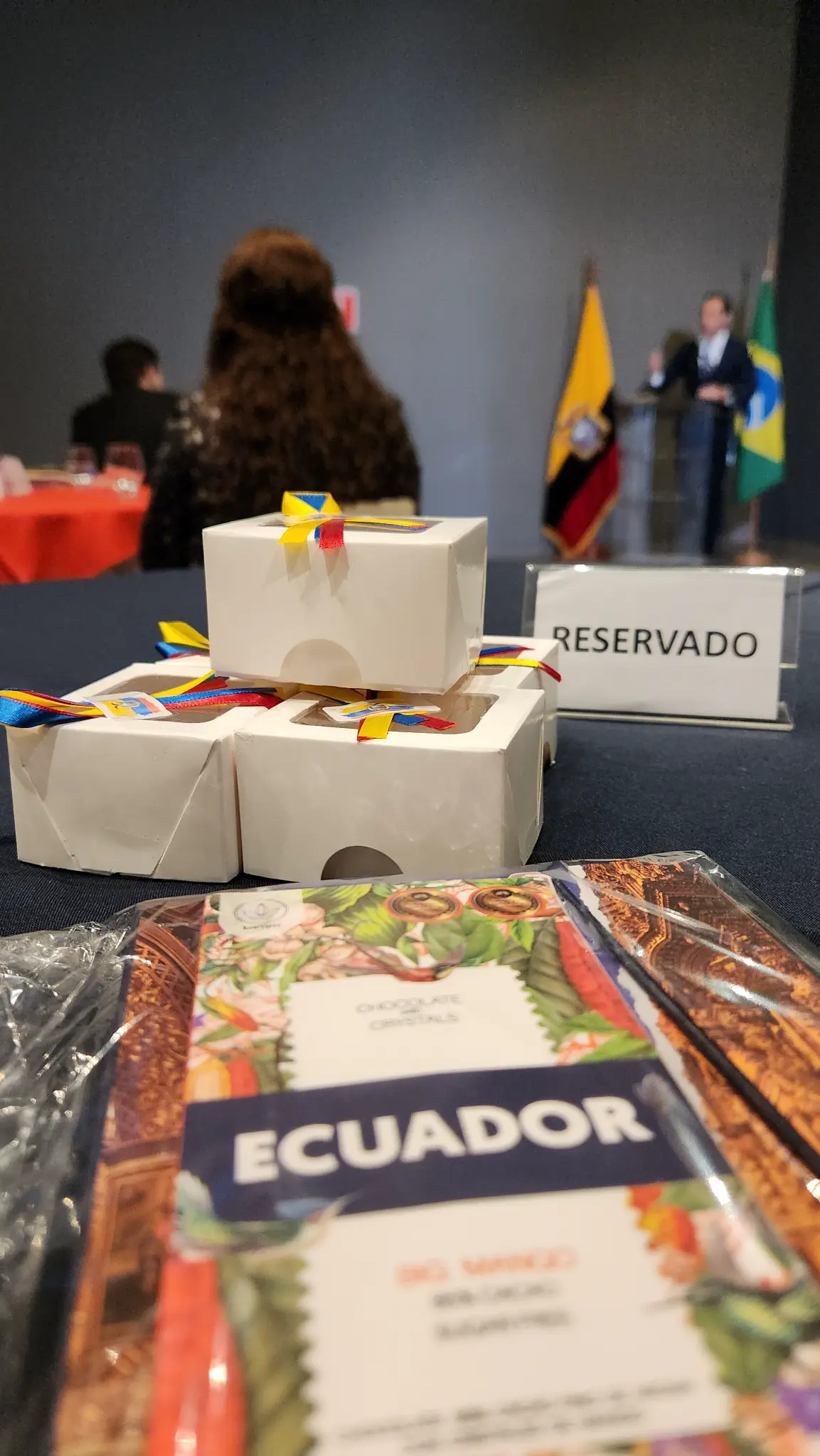 Chocolates identificados como Ecuador, cajas con cintas tricolores y un cartel de reservado ante la ceremonia