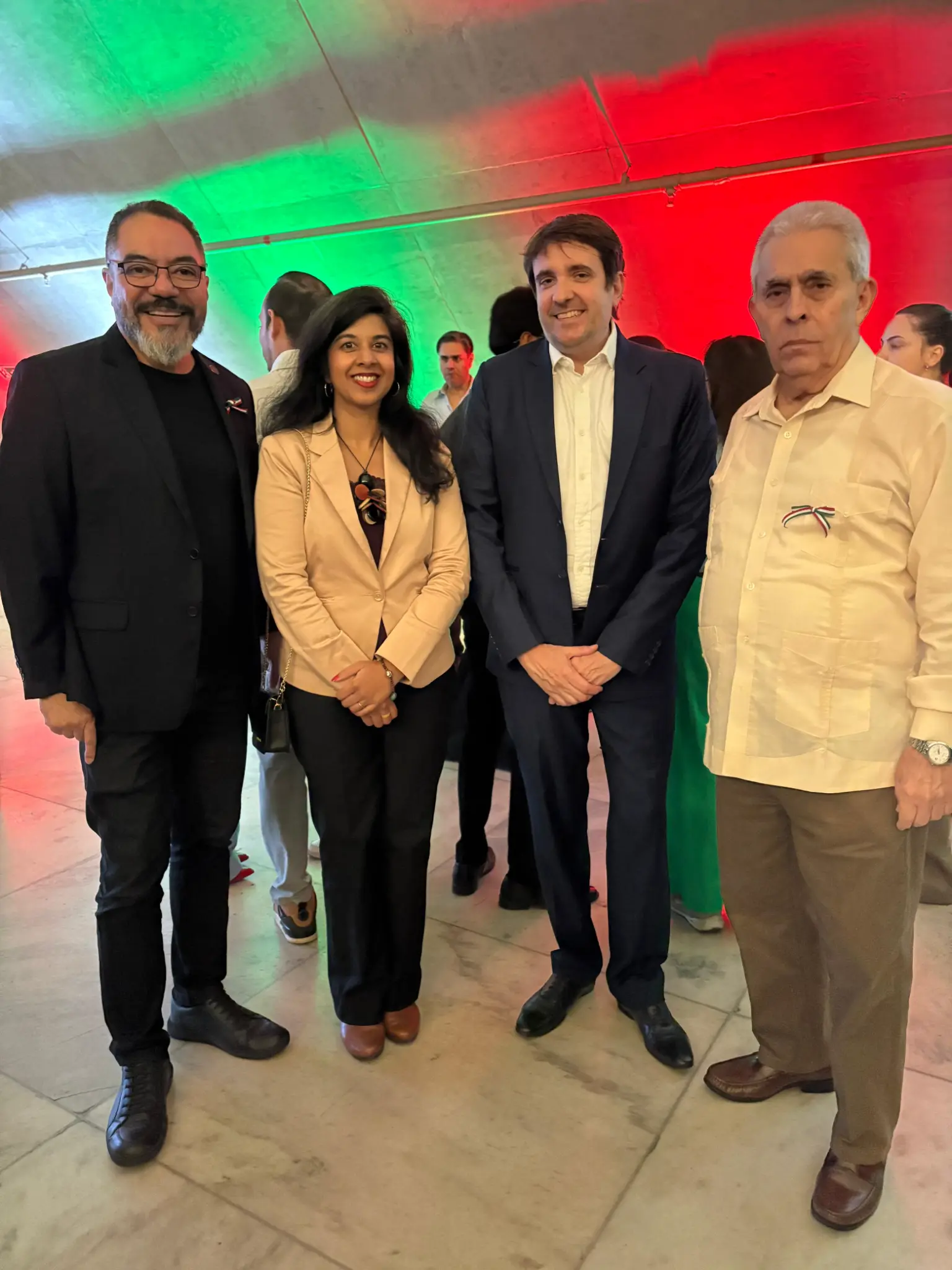 João Carlos Corrêa, Prisca Ramesh y dos diplomáticos posan en un ambiente iluminado en colores verde y rojo durante una celebración mexicana