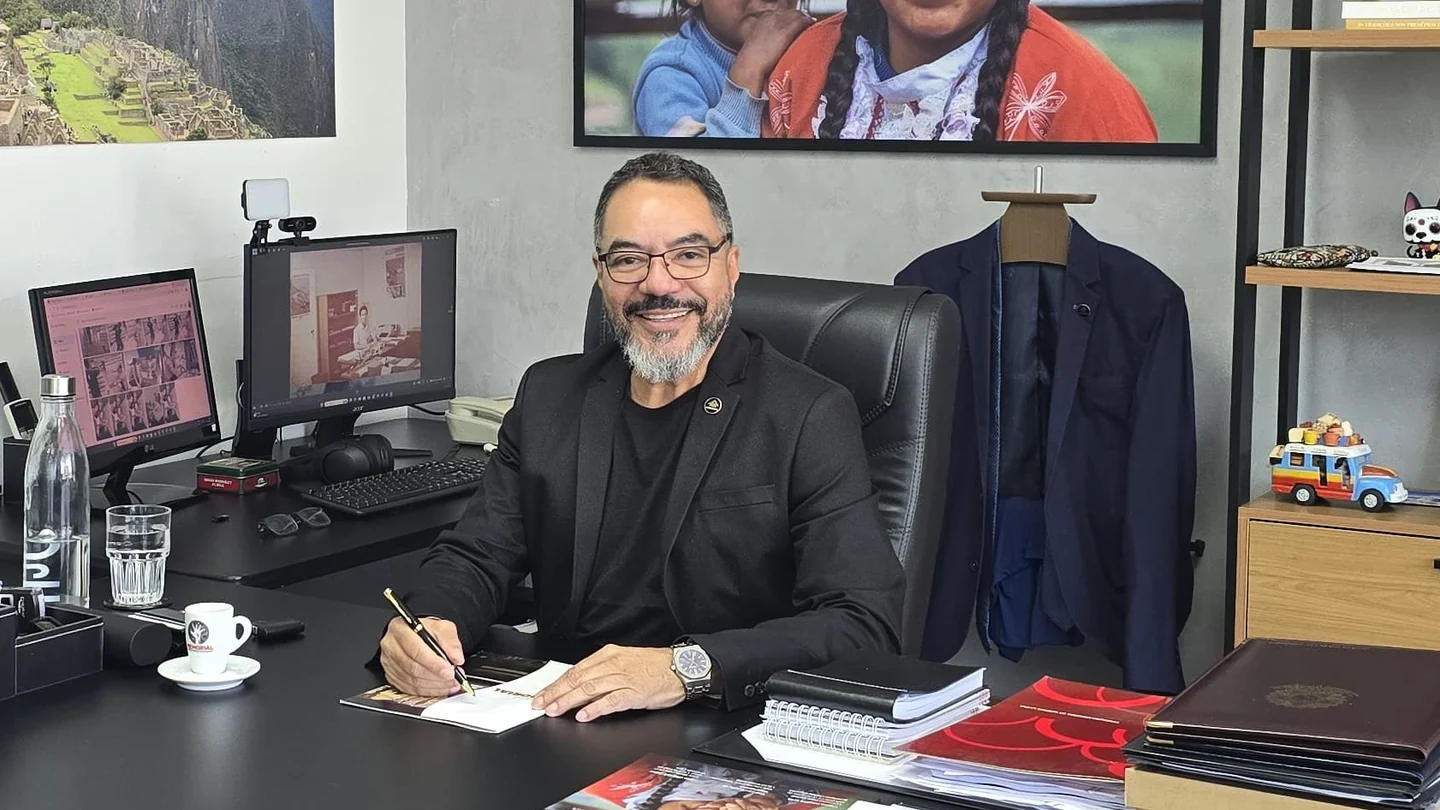 João Carlos Corrêa sentado em seu ambiente de trabalho executivo, sorrindo e segurando uma caneta