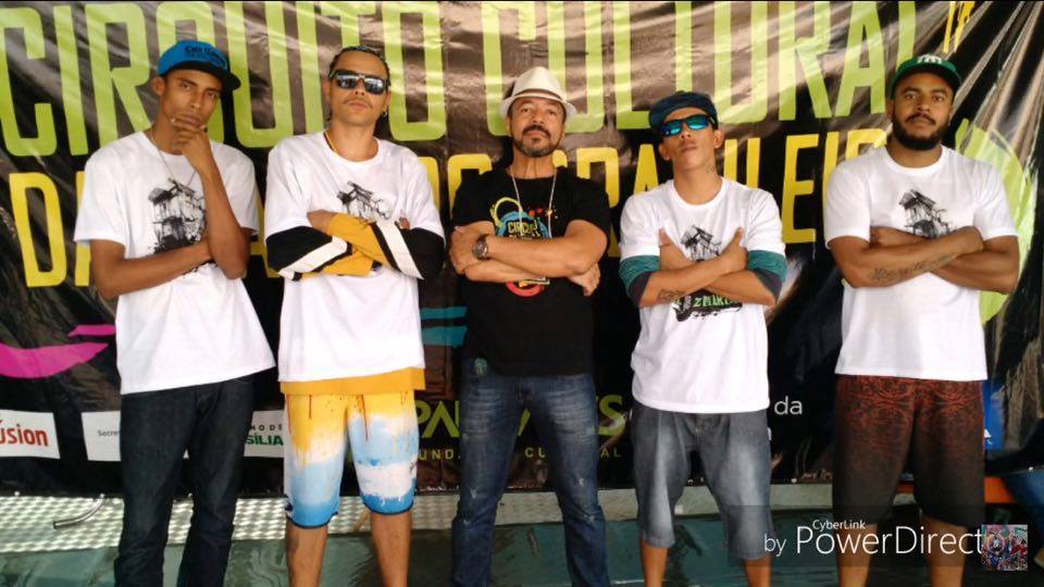 João Carlos Corrêa posa com quatro jovens artistas diante do painel do Circuito Cultural de Danças Afro-Brasileiras