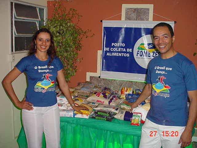 Dois integrantes da organização junto ao posto de coleta de alimentos da campanha Fome Zero