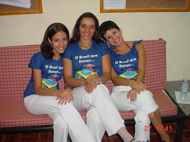 Três participantes com camisetas azuis da I Maratona de Dança sentadas em um sofá