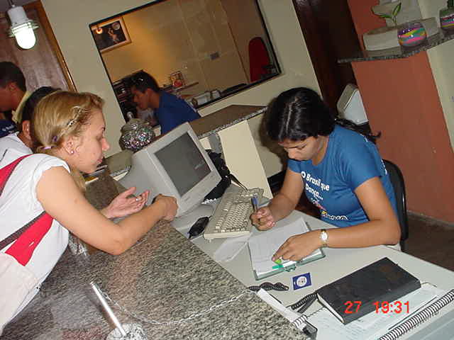 Duas integrantes trabalham junto ao computador na recepção do evento