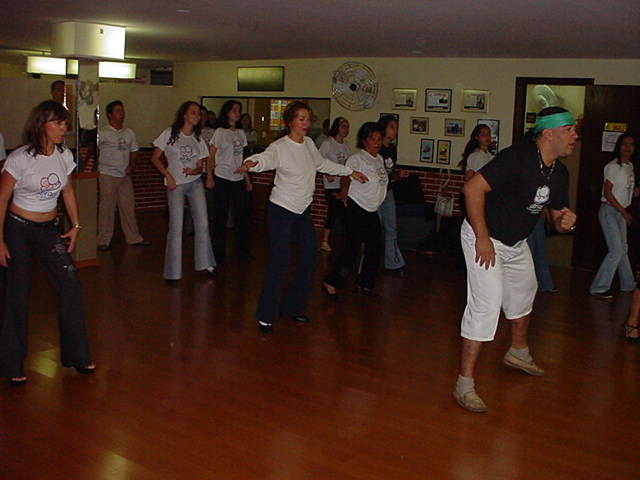 Grupo de participantes acompanha atividade de dança em formação no salão