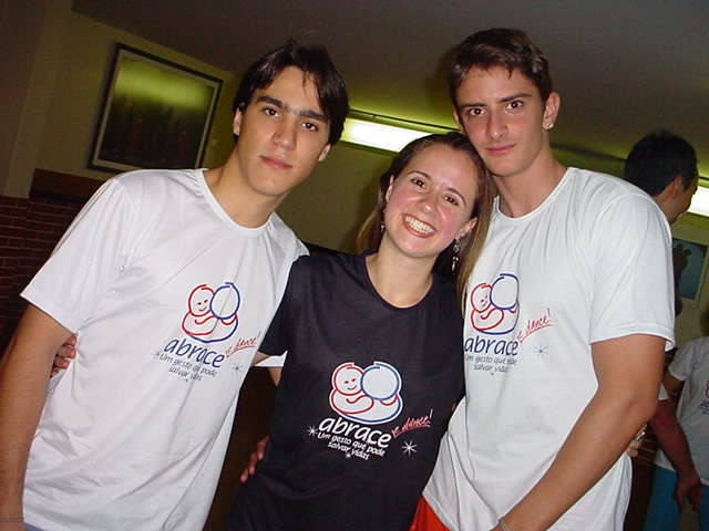 Três participantes com camisetas da campanha ABRACE reunidos em retrato