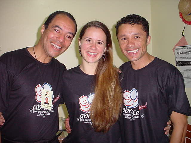 Três integrantes com camisetas escuras da campanha ABRACE reunidos em retrato