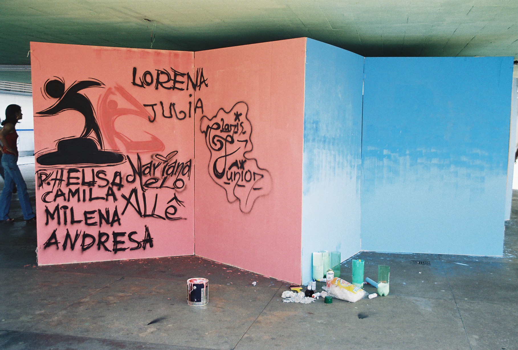 Painel pintado durante oficina artística com nomes e materiais dispostos no piso