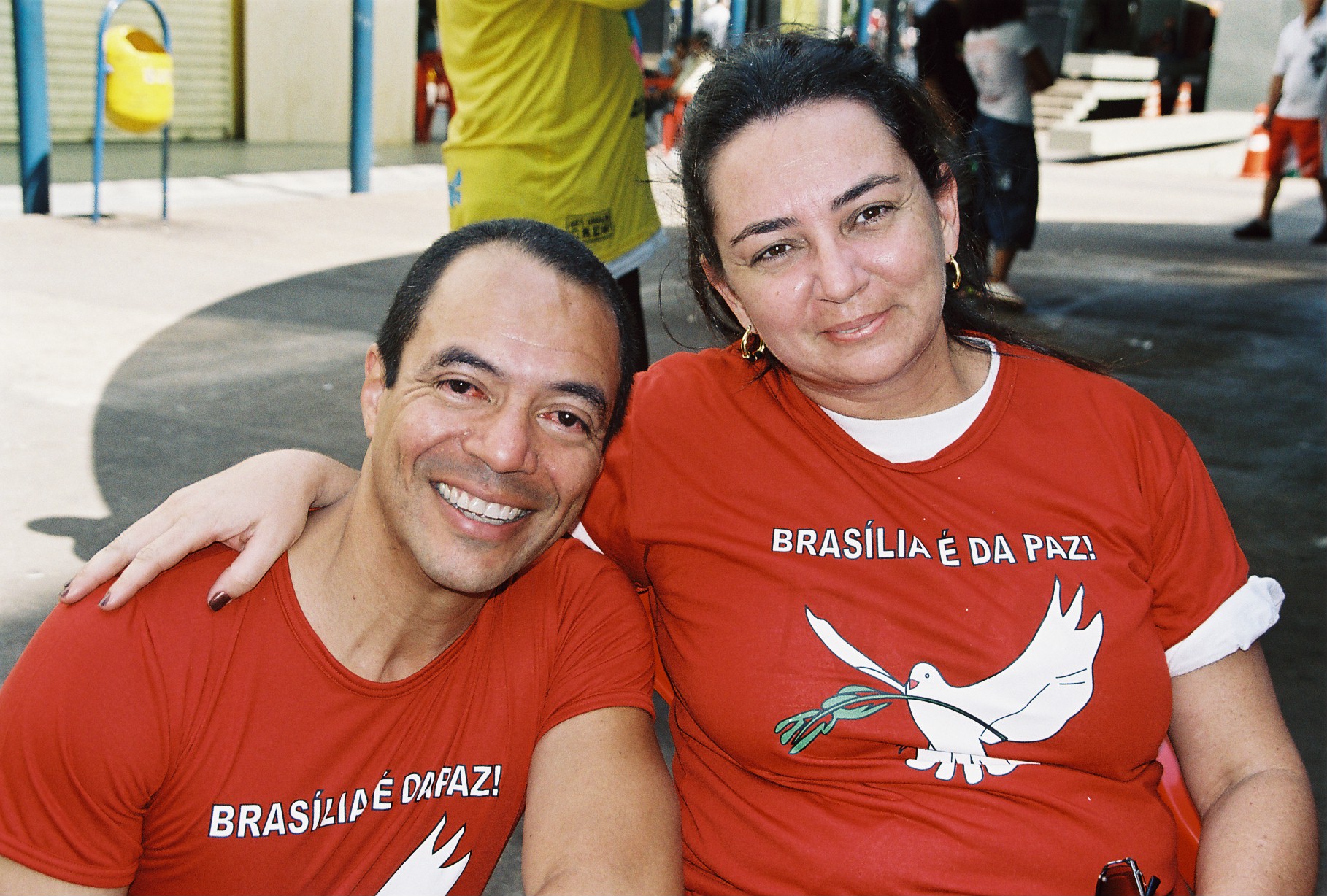 Dois integrantes com camisetas vermelhas Brasília é da Paz reunidos em retrato