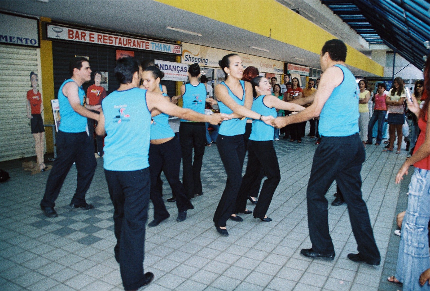 Grupo com figurinos azuis executa sequência de dança diante do público