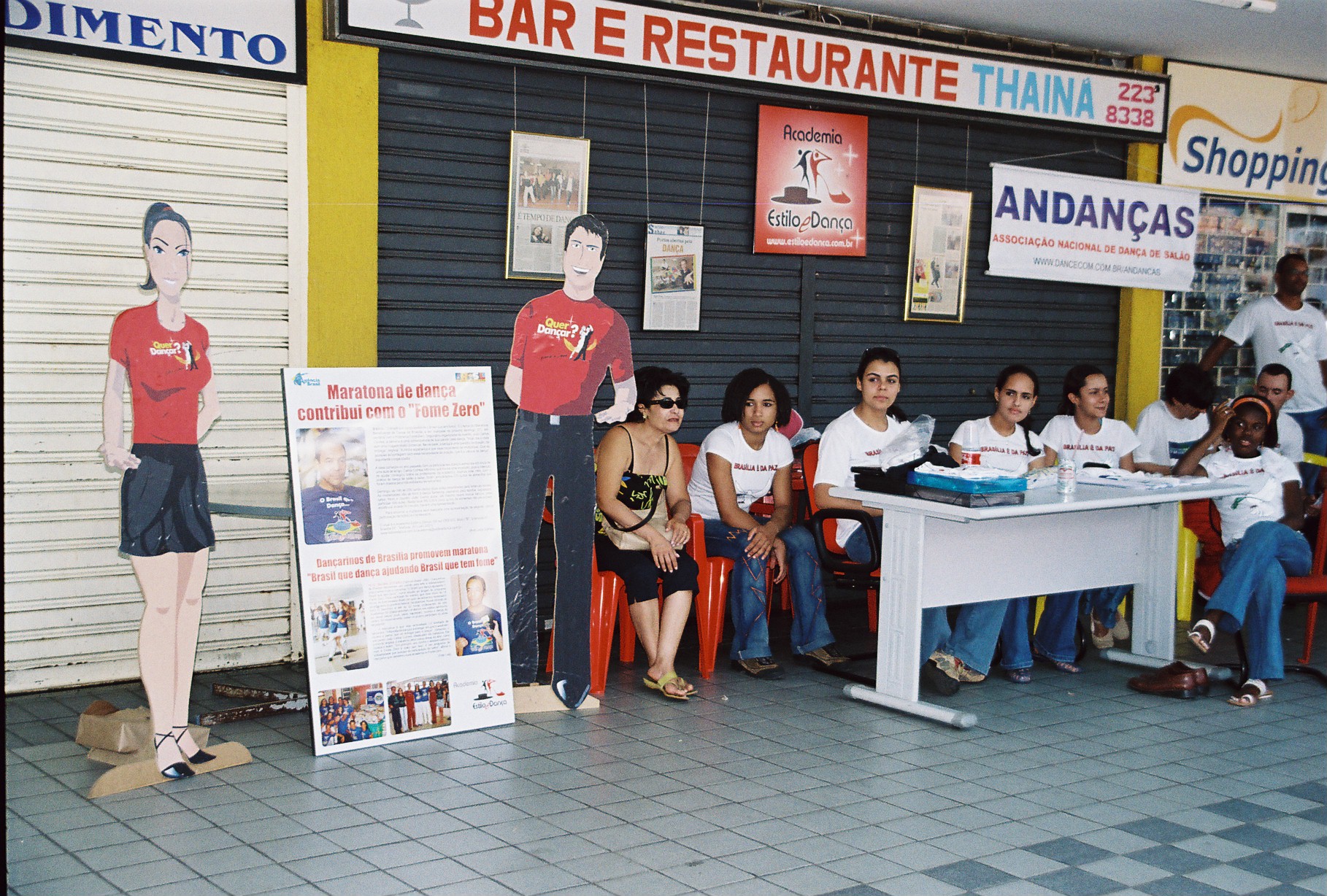 Equipe reunida em mesa de atendimento junto aos materiais de divulgação do evento