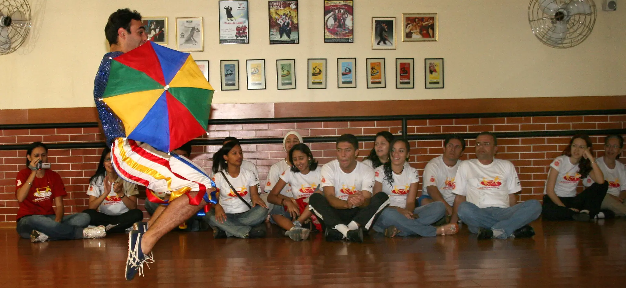 Artista apresenta número com guarda-chuva colorido diante do público