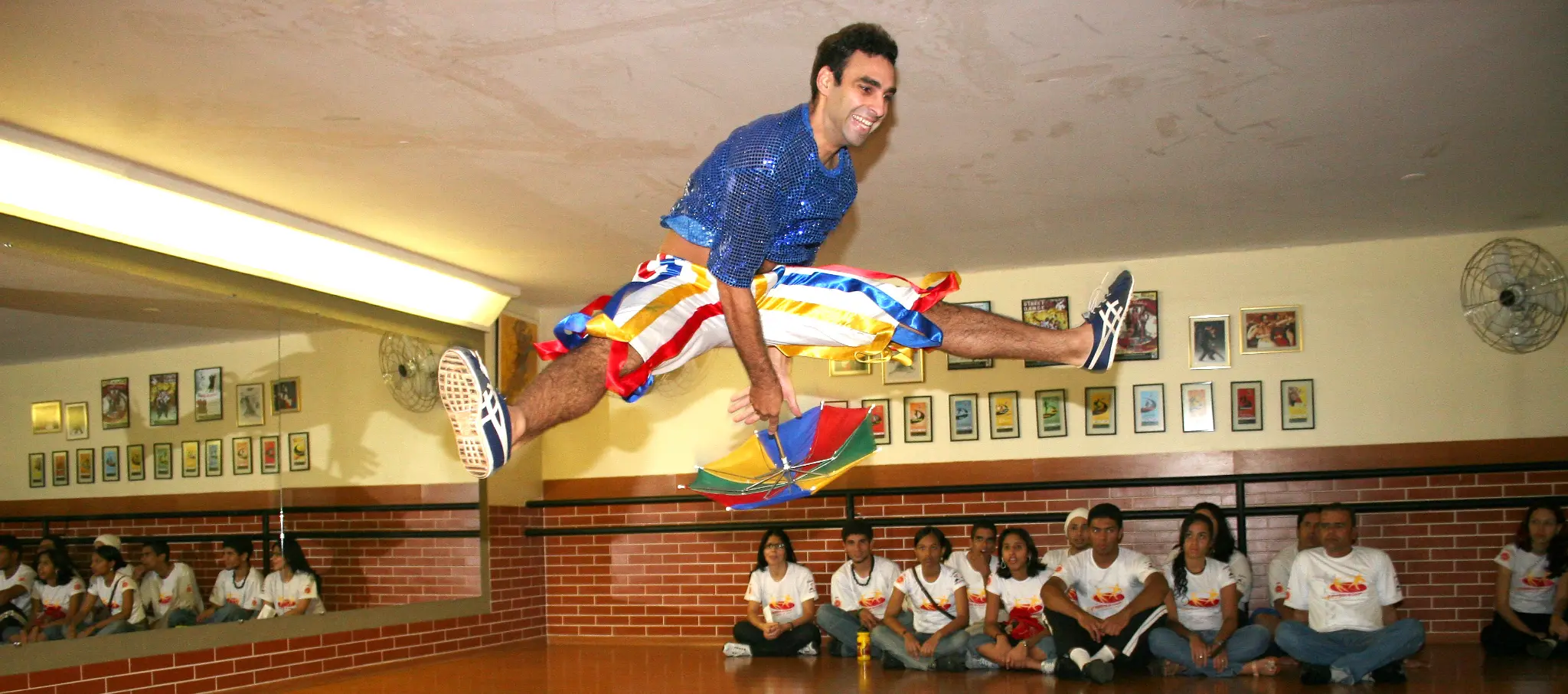 Artista executa salto acrobático diante dos participantes reunidos no salão