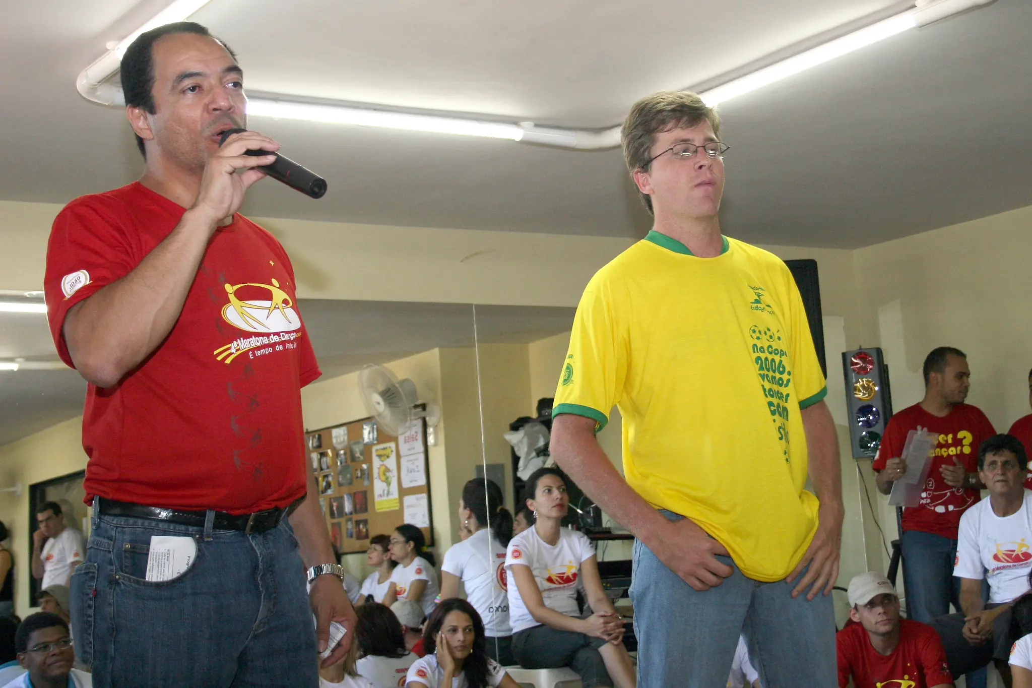 Dois integrantes conduzem fala diante dos participantes reunidos