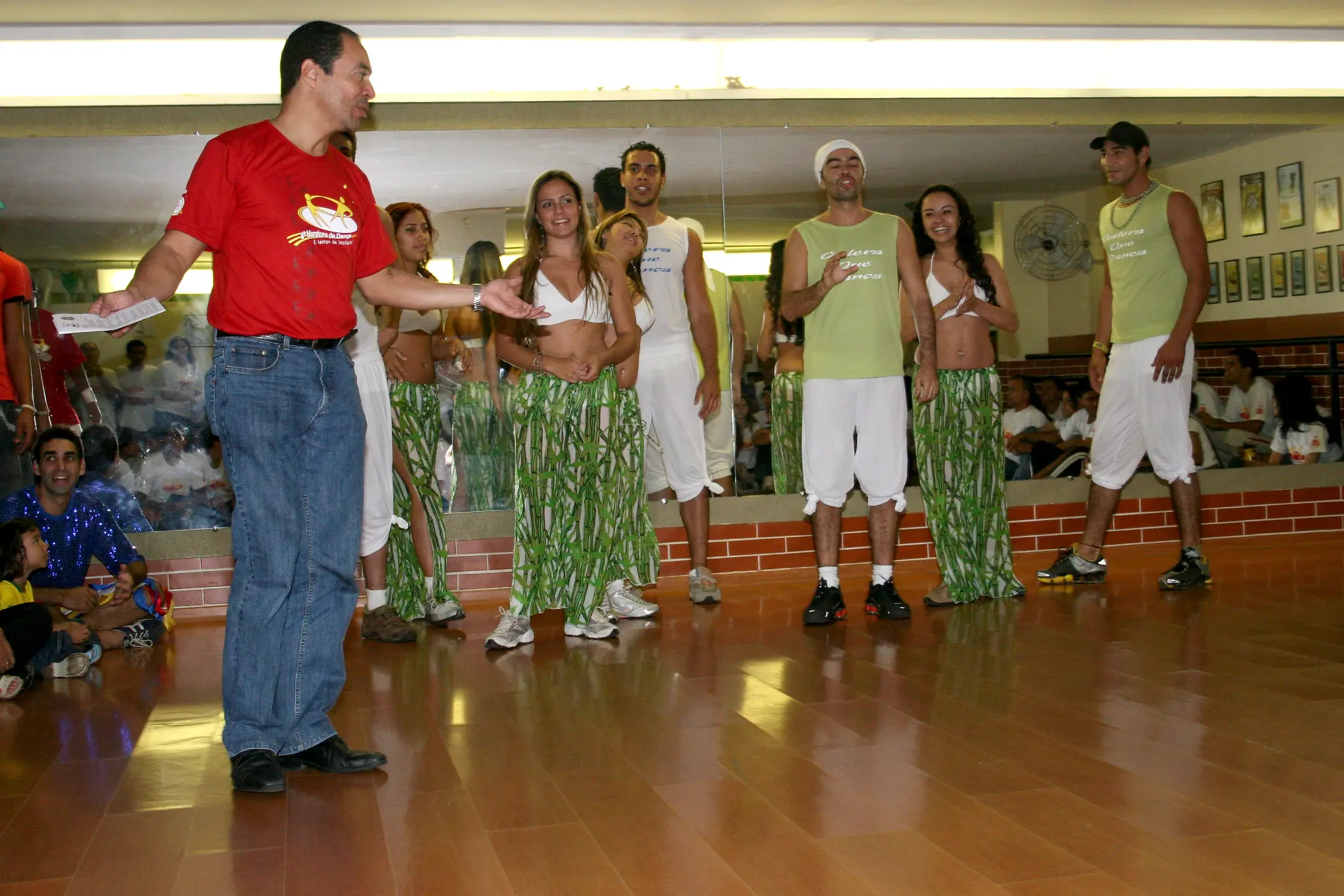 Grupo com figurinos verdes acompanha apresentação diante do público