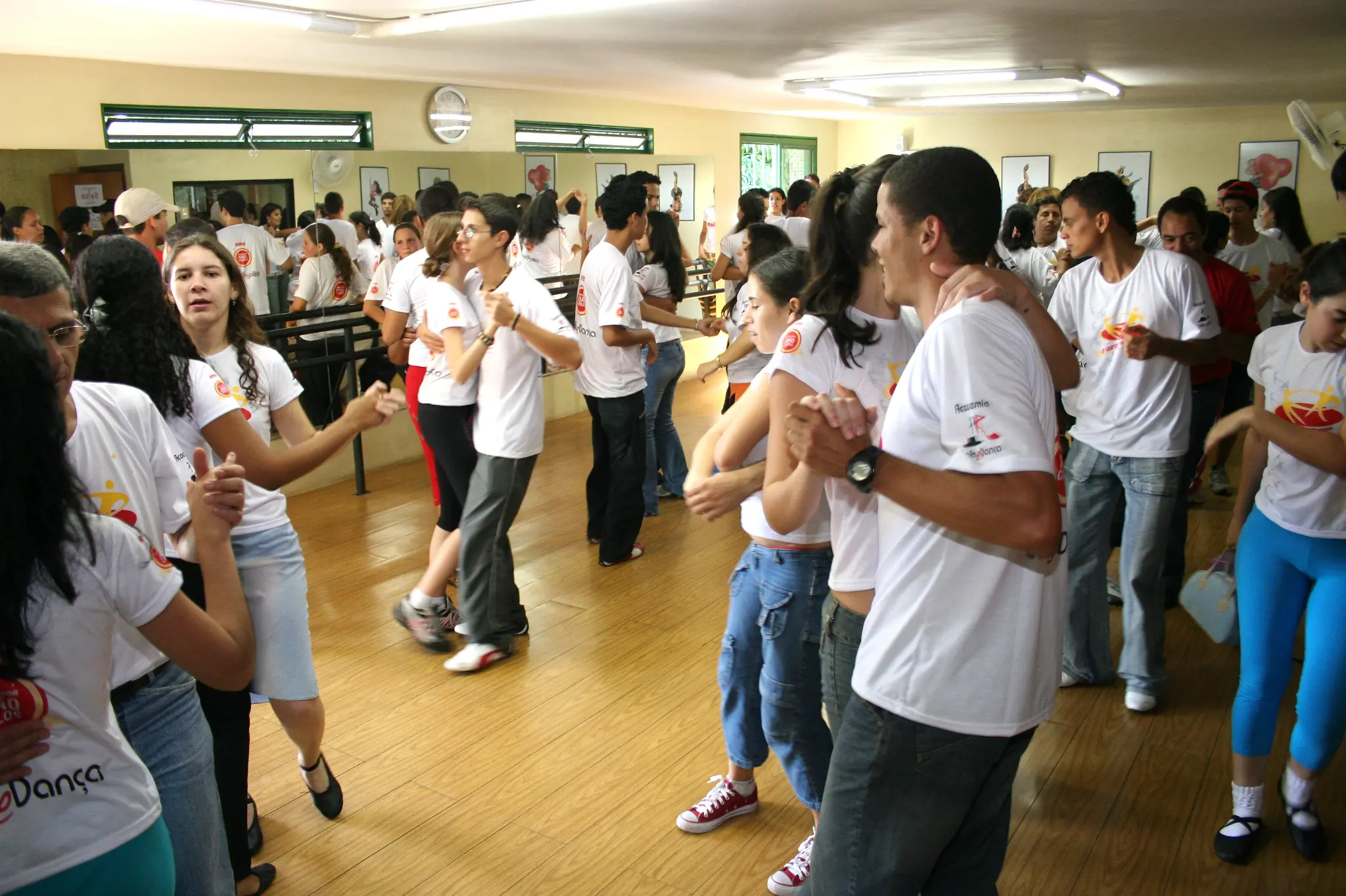 Participantes praticam dança em pares durante atividade no salão