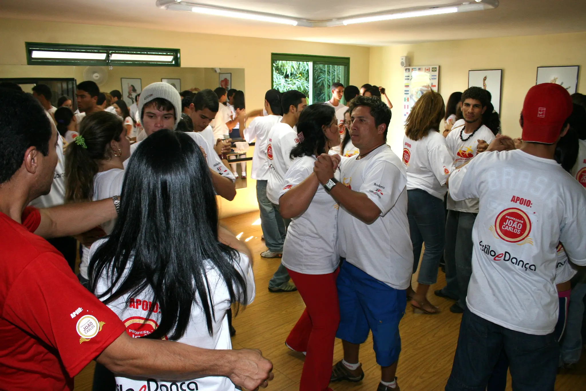 Salão ocupado por duplas e grupos em prática de dança